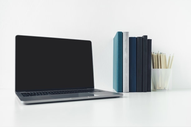 笔记本电脑模拟与空白或空白屏幕与书或教科书堆栈的拷贝空间。使用笔记本电脑在网上进行商务工作或教育学习图片下载