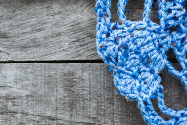 蓝色地毯的细节视图与地板的心脏形状，手工编织，在灰色的木制背景。木房间地板上桌布的一角。图片下载