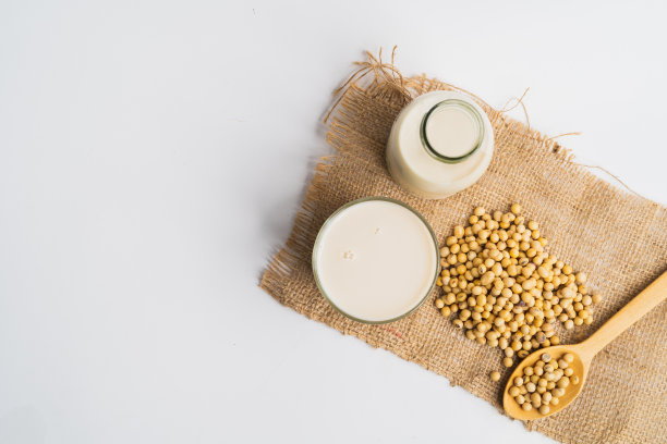 豆浆的健康益处，豆浆在玻璃和大豆孤立俯视白底图片下载