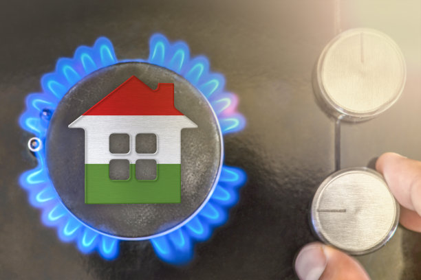 供暖季节或燃气在匈牙利的使用。概念，一个房子的模型站在一个燃气锅炉的火焰附近在黑色的背景。在匈牙利使用天然气的成本。图片下载