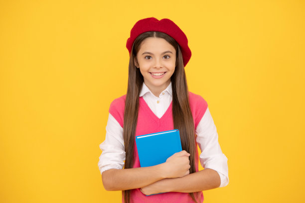 回到学校。戴着贝雷帽的开朗孩子准备学习了。微笑的孩子拿着书。十几岁的学生。图片下载