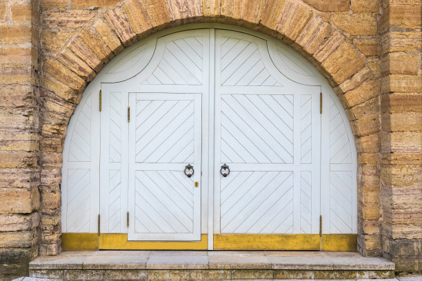 半圆形石拱下的一扇大的仿古双叶木门。图片下载