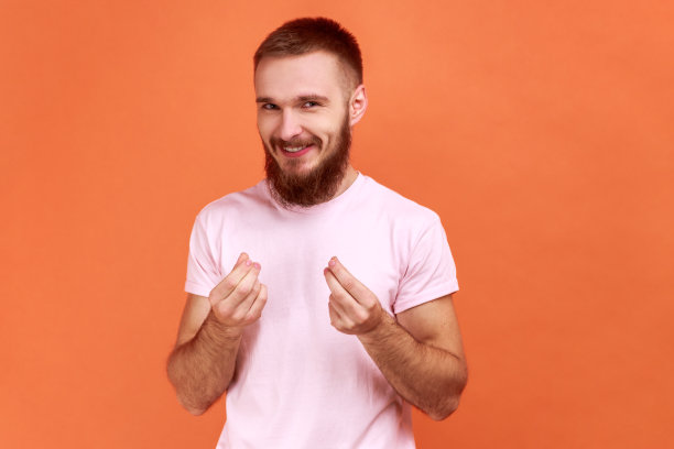 男人站着看着相机与金钱或意大利手势的手。图片下载