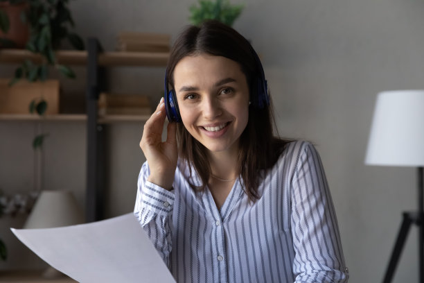 戴着无线耳机微笑聪明的年轻女商人的肖像。图片下载