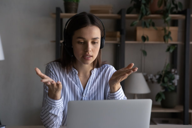 专注的年轻女子戴着耳机召开视频会议。图片下载