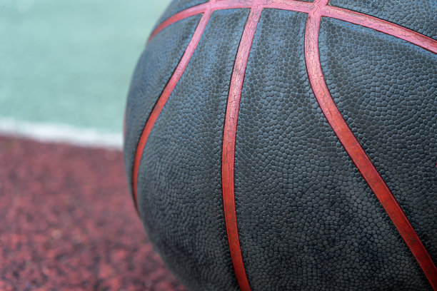 地上有一个黑色的篮球。红色球场上的特写球。在街上或室内球场打篮球。没有人的运动装备。极简主义。模板,运动背景图片下载