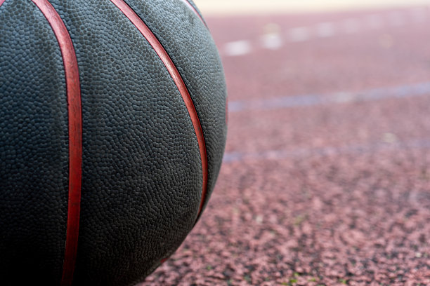 地上有一个黑色的篮球。红色球场上的特写球。在街上或室内球场打篮球。没有人的运动装备。极简主义。模板,运动背景图片下载