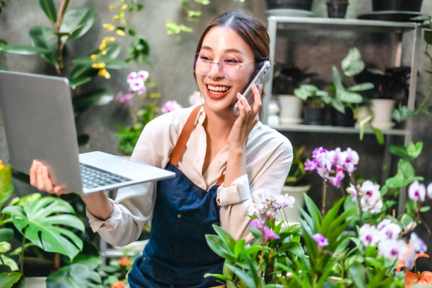 亚洲美丽的年轻女子在花盆上用智能手机拍小树的照片在家里出售。在线销售的概念。图片下载