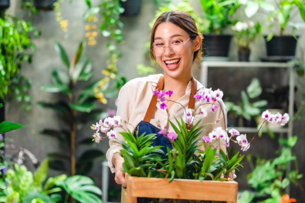 亚洲美丽的年轻女子在花盆上用智能手机拍小树的照片在家里出售。在线销售的概念。图片下载