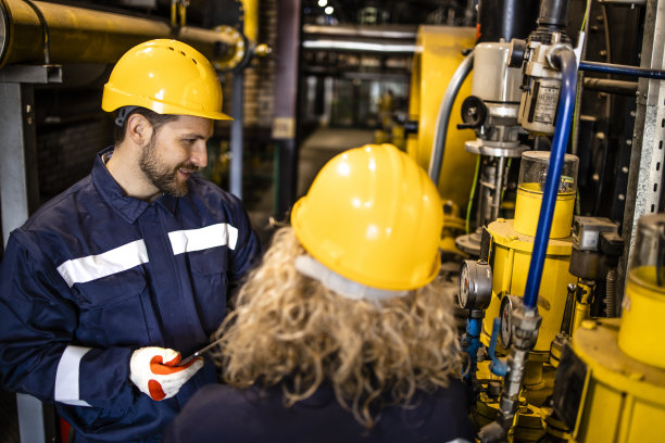 在炼油厂一起工作的产业工人控制天然气管道装置。图片下载