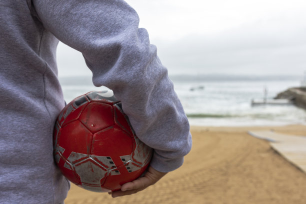 沙滩上一个男人腋下的足球。图片下载
