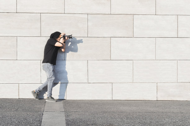 白人男性摄影师，白天拍摄，灰色背景墙和复制空间图片下载