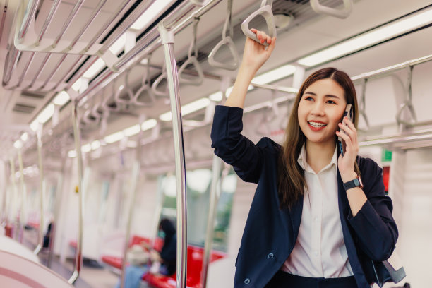 亚洲女商人在去办公室的火车上坐着打电话。图片下载