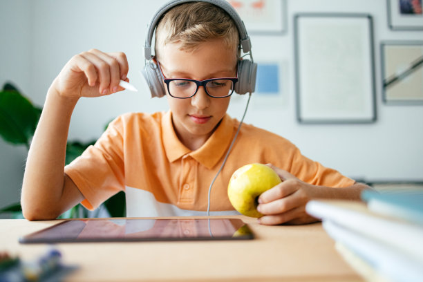 快乐男孩在家吃苹果时用平板电脑图片下载