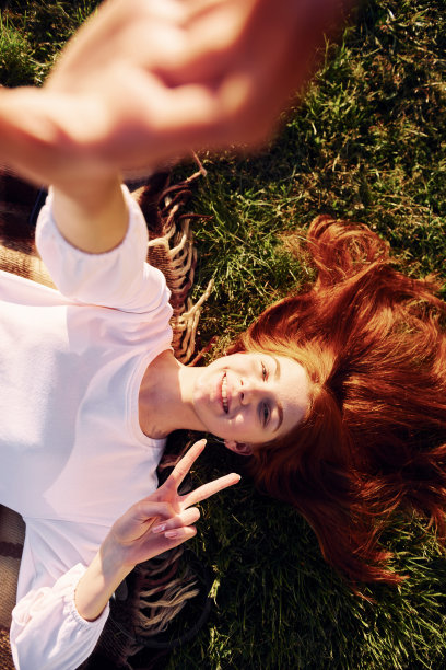 躺下来自拍。前视图。年轻的女孩在阳光明媚的白天在球场上度过美好的周末图片下载