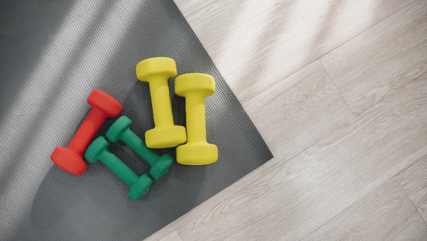 家居保健概念，运动器材，木制地板上有哑铃和瑜伽垫，从上面看，平视。图片下载