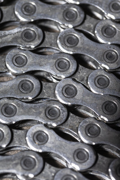 石质背景下作为金属自行车设备一部分的废旧油链的详细特写，细节对比图片下载