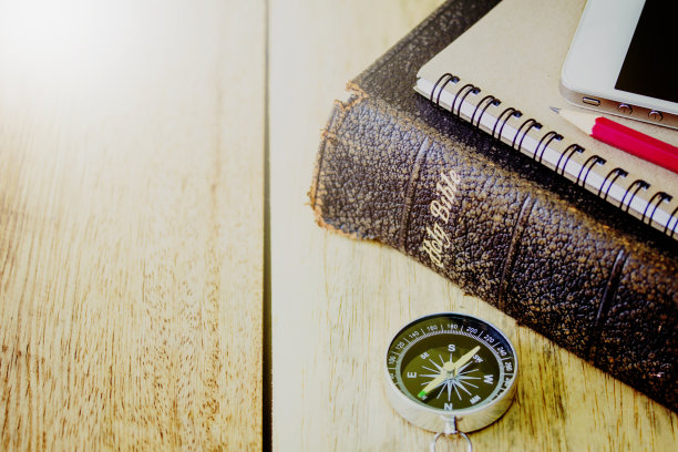 指南针和圣经，笔记本，铅笔，智能手机放在木桌上图片下载