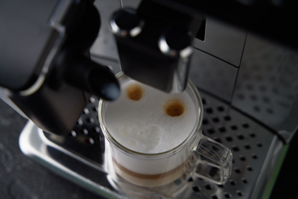 现煮的卡布奇诺从咖啡机中倒入玻璃杯中。图片下载