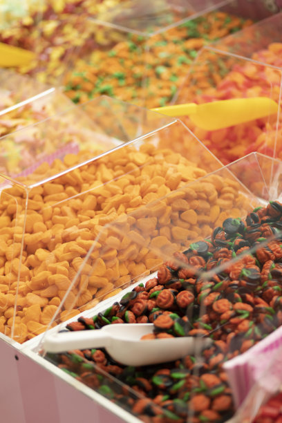 彩色的亮橙绿果冻棒棒糖(糖果)在透明的盒子和勺子陈列在糖果店。低糖水果软糖，颜色来自水果和蔬菜。垂直平面图片下载