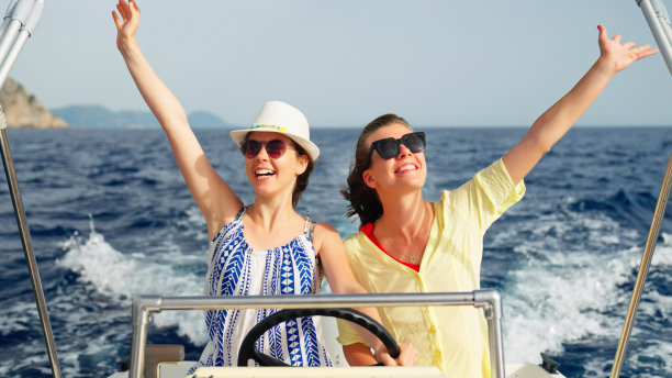 女性朋友在梦想的假期中享受快艇之旅。张开双臂，露出愉快的微笑图片下载