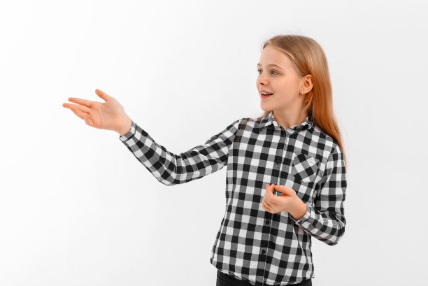 可爱的十几岁女孩的肖像，指着左手，看着产品，显示徽标或横幅出售，站在白色背景图片下载