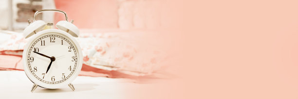 经典设计白色闹钟显示时间大约在早上7点在床上亚麻粉粉彩色调的背景。图片下载