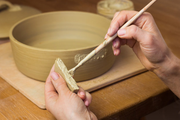 陶艺课上，女陶艺家在锅上安装把手。陶艺工作室的陶工车间图片下载