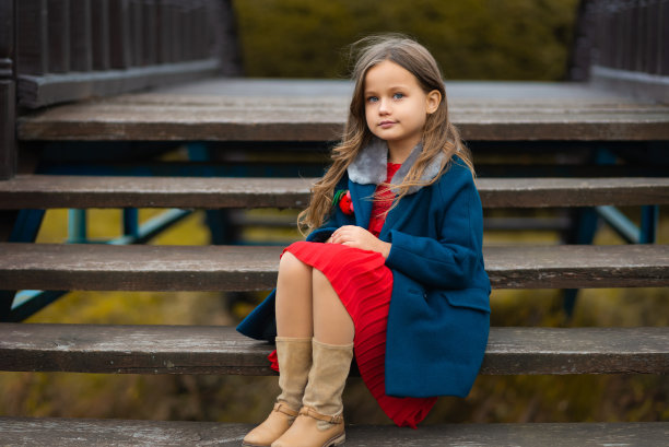 可爱的女孩坐在公园的楼梯上看着镜头图片下载