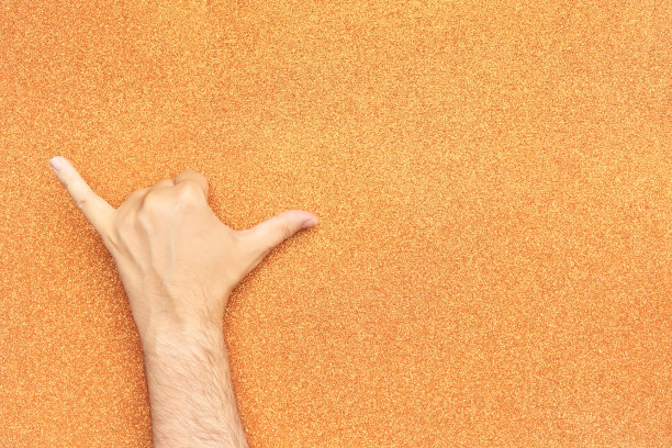 放松或喝酒的手势在男人的手闪光的橙色背景图片下载