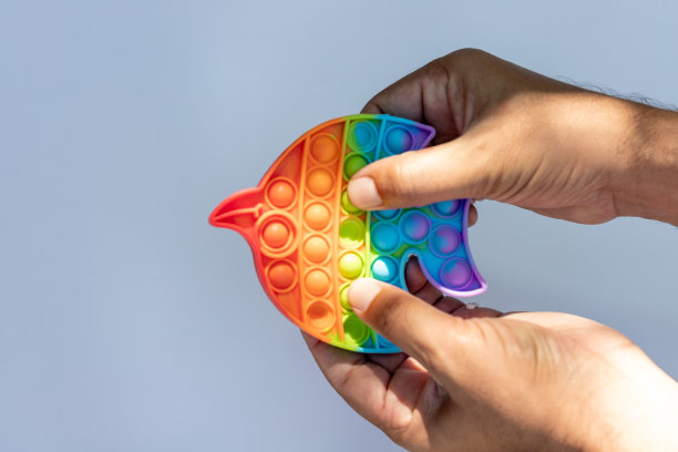 一个彩色的抗压力的感官玩具，指尖推pop它的游戏握在手中图片下载