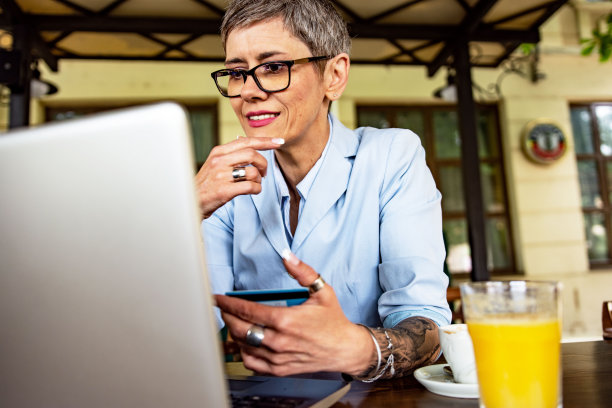 成熟女性坐在咖啡店用笔记本电脑网购图片下载