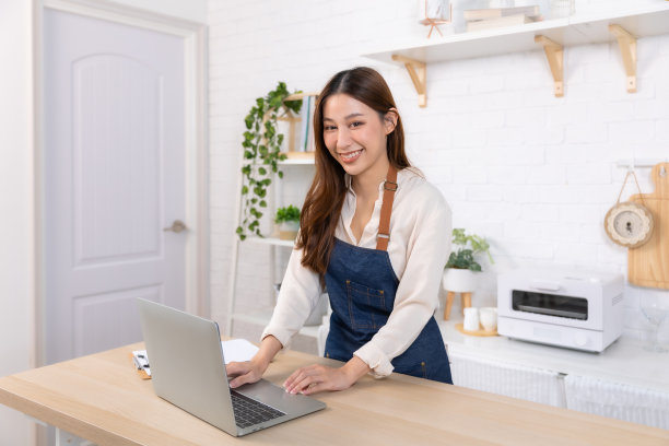 快乐而开朗的女人坐在沙发上用电话。亚洲年轻女子看手机在家里网上购物。图片下载