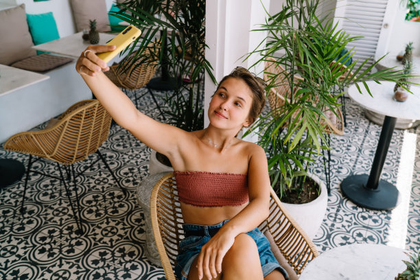 放松的女士在阳台上用手机图片下载