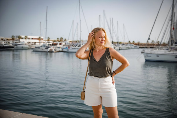 在游艇的背景下，一个心满意足的女人在海边放松图片下载