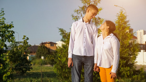 年轻的残疾妇女和男子牵手微笑在夕阳图片下载
