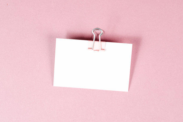 在一张粉色背景的白纸上放一个回形针，在办公室里复制文字，提醒或信息，交流概念图片下载