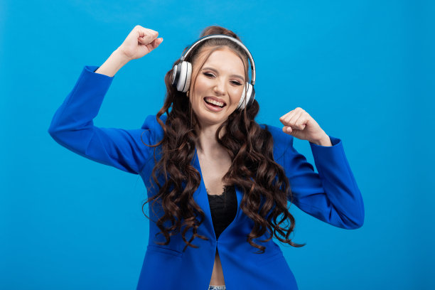 一个有趣的快乐的年轻女孩的肖像，戴上现代技术的耳机，听流行歌曲，在一个好心情，跳舞图片下载