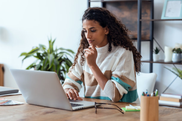 集中美丽的商业女性工作与笔记本电脑，同时喝咖啡在家里的客厅。图片下载