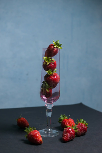 新鲜的草莓放在一个漂亮的杯子里，黑色的背景上有会飞的浆果。主音。有选择性的重点。大气夏天的背景，心情。夜总会和夏季聚会的广告。图片下载