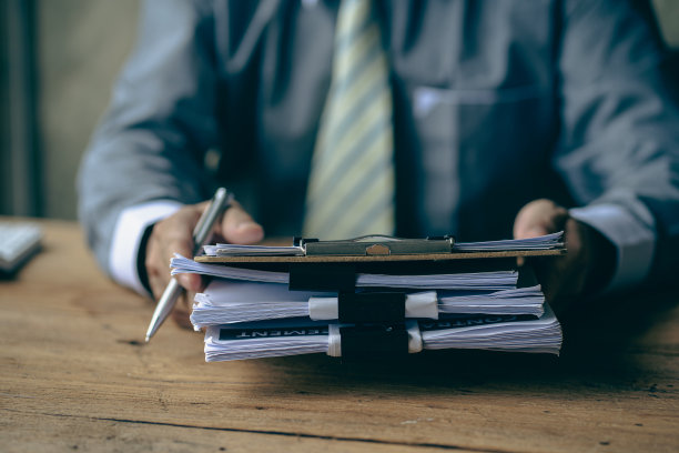 商人在财务会计工作与成堆的文件在家里的桌子上工作从家里的概念，业务报告，堆未完成的文书图片下载