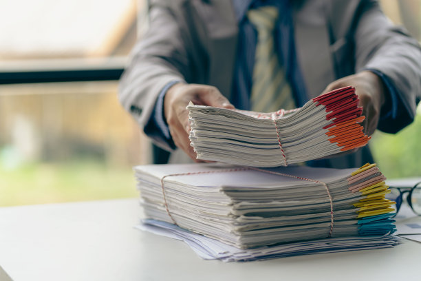 商人在财务会计工作与成堆的文件在家里的桌子上工作从家里的概念，业务报告，堆未完成的文书图片下载