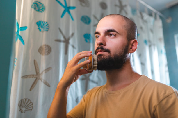 一个秃顶的年轻人在浴室镜子前刷胡子的特写图片下载