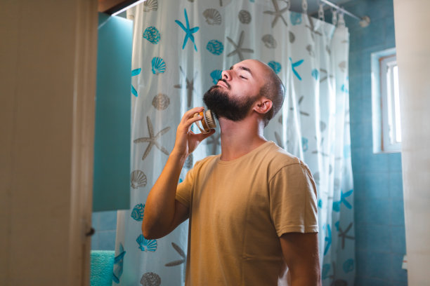 秃顶的年轻人在镜子前刷胡子图片下载