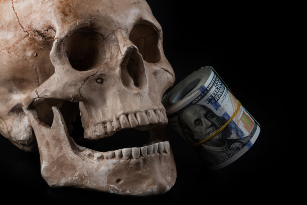 一个人头骨模型和一盒美元图片下载