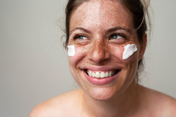 一个长着雀斑的漂亮女人在照顾她的脸图片下载