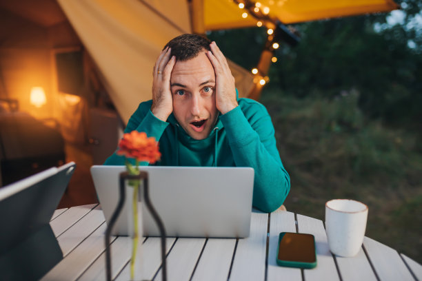 一个夏天的晚上，自由职业者在舒适的野营帐篷里使用笔记本电脑。用于户外度假和度假的豪华露营帐篷。生活方式的概念图片下载