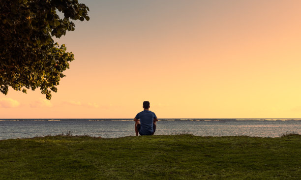 日落时分坐在沙滩上的男人。图片下载