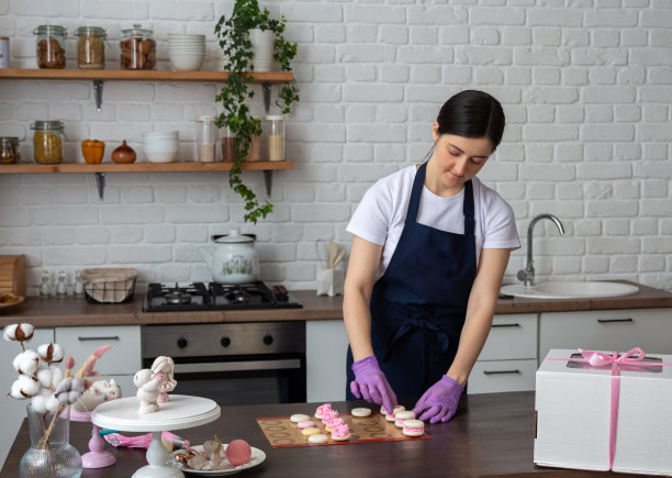 女糕点师在餐桌上收集马卡龙。有选择性的重点。关于甜点、食物的网站照片。图片下载