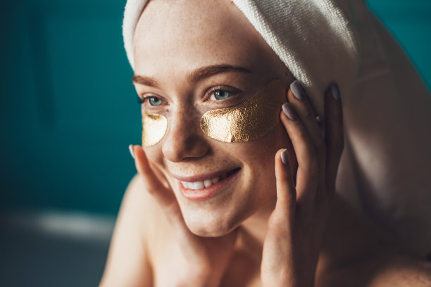 有雀斑的女人在眼睛下面用手触摸脸。自然美景。皮肤护理。复兴的治疗。眼部护理。图片下载